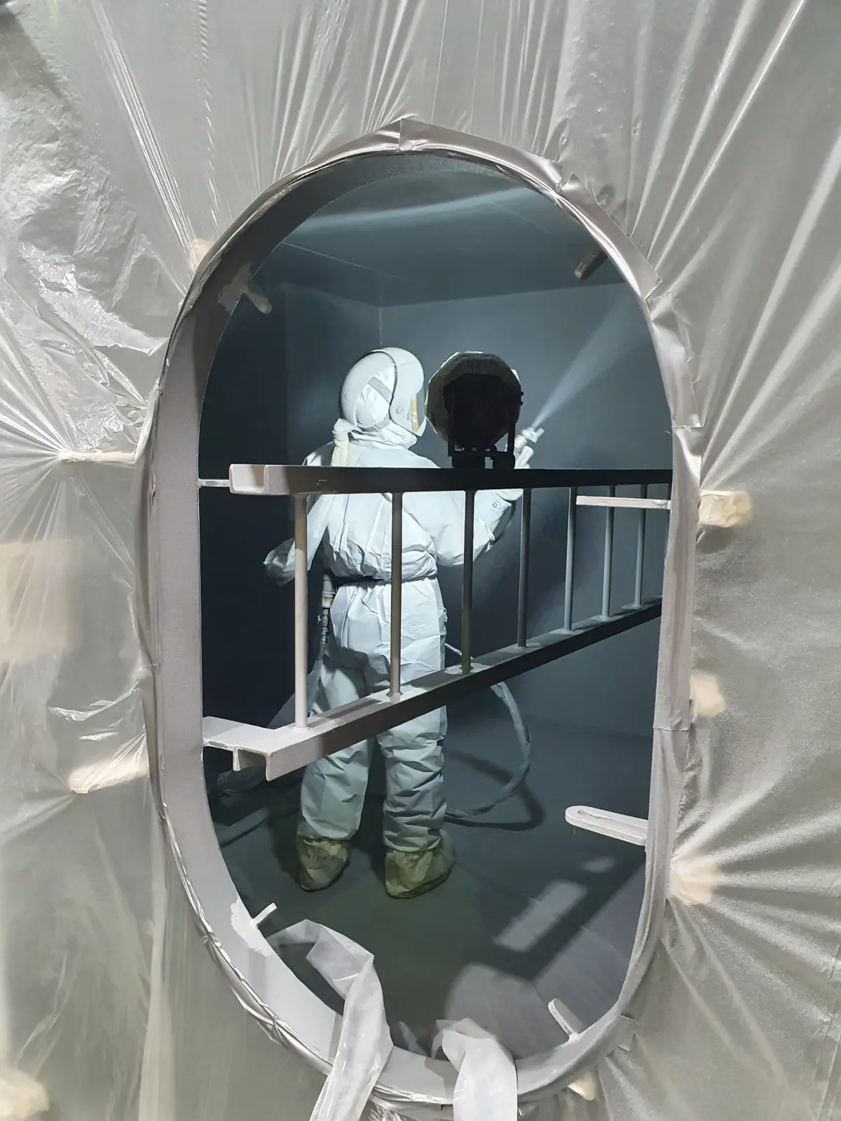 Handmatig spuiten van complexe staalconstructies in beschermend pak